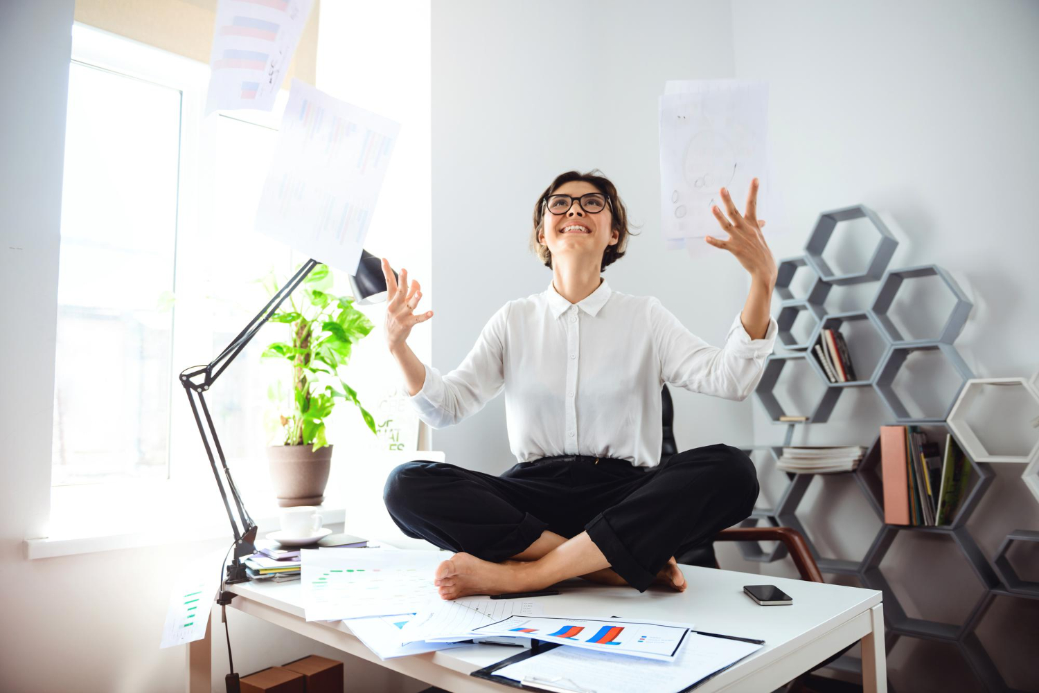 young-beautiful-businesswoman-glasses-smiling-throwing-up-papers-sitting-table-workplace-office